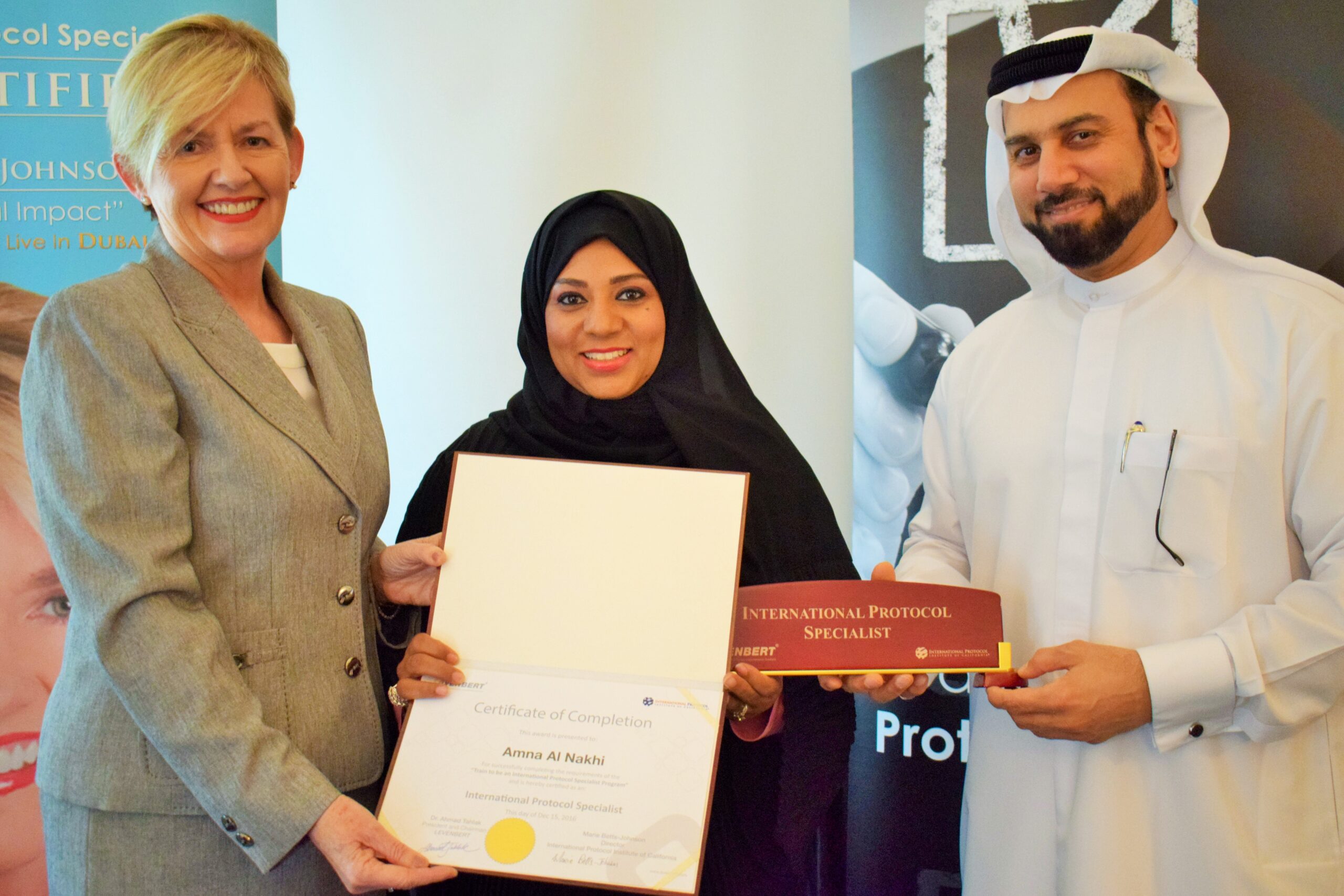 Marie presenting a certificate to a man and a woman