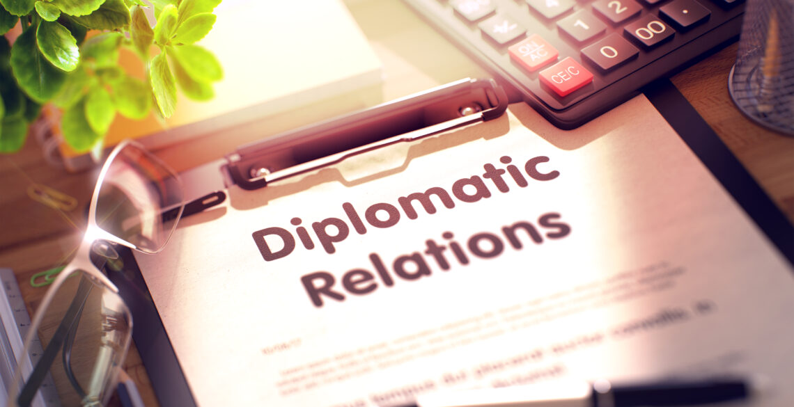 Document titled 'Diplomatic Relations' on a clipboard with a pen and keyboard nearby.