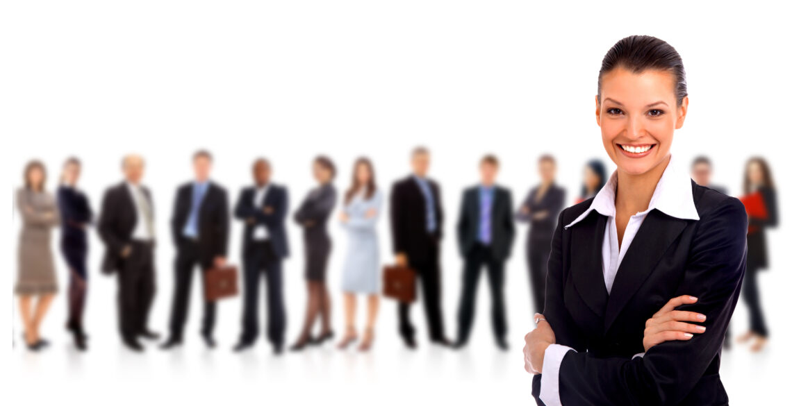 Businesswoman smiling confidently with a team in the background.