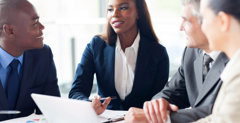 A businesswoman discussing with colleagues in a meeting.