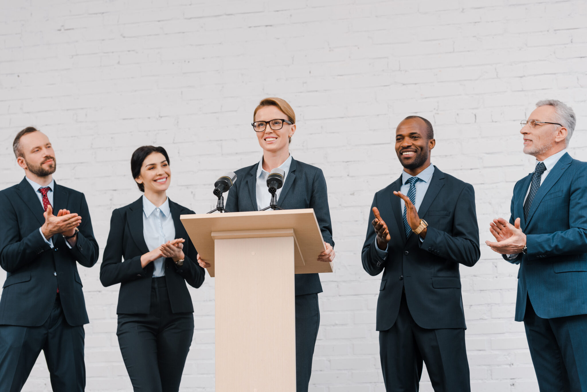 A woman speaking on the mic, other people clapping